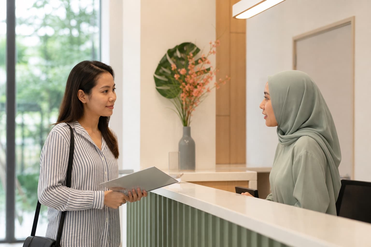 A Malaysian patient checking in for an appointment at a modern medical clinic in Johor Bahru